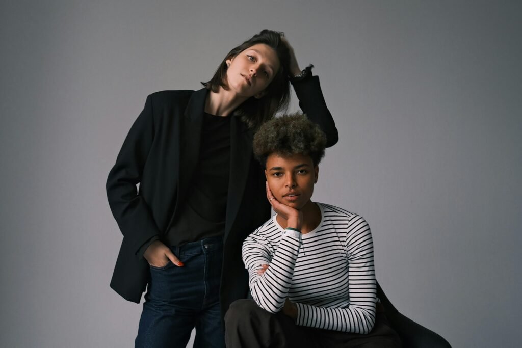 A modern portrait of two stylish adults in casual and elegant attire posing indoors.